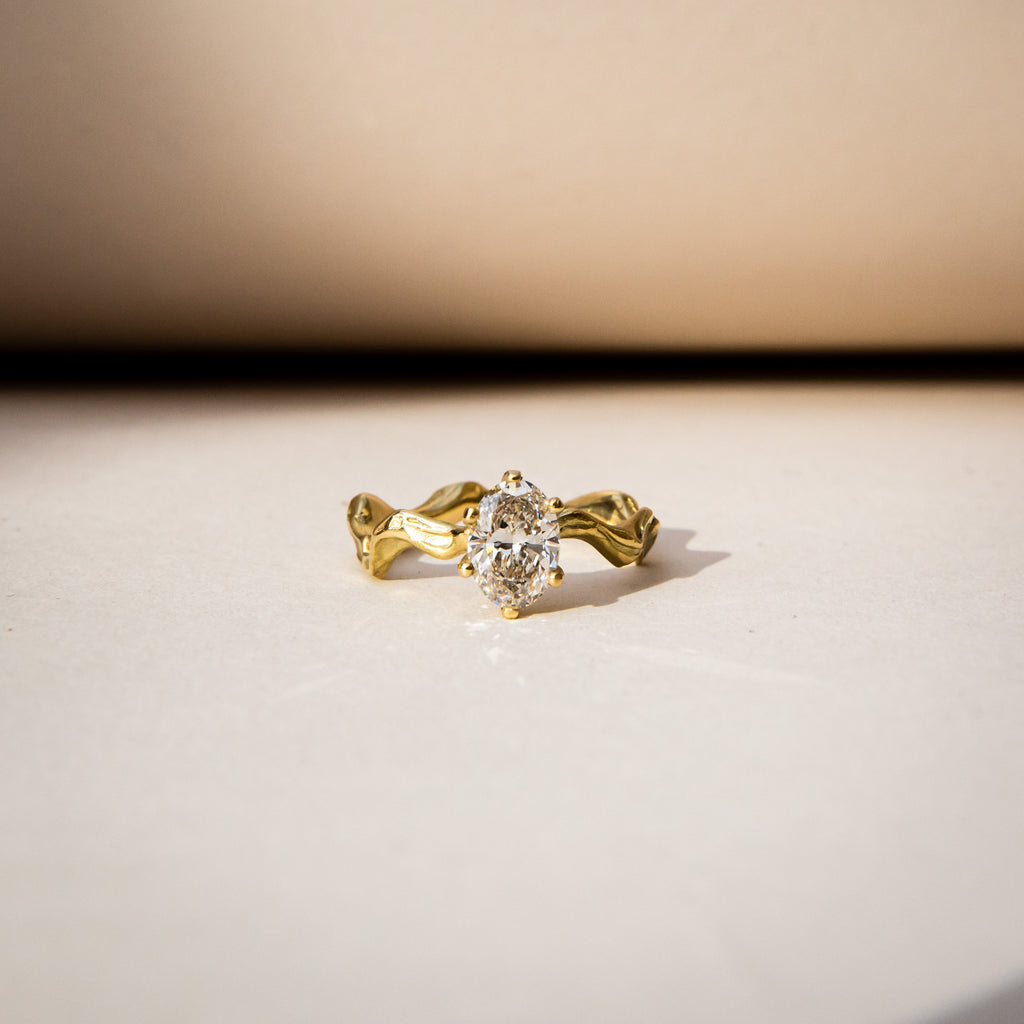 Oval diamond on a textured, wavy 18ct yellow gold band