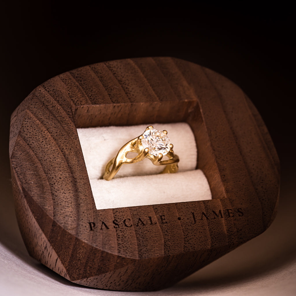 18ct fairtrade yellow gold and diamond ring sat within a dark wood walnut wooden jewellery box