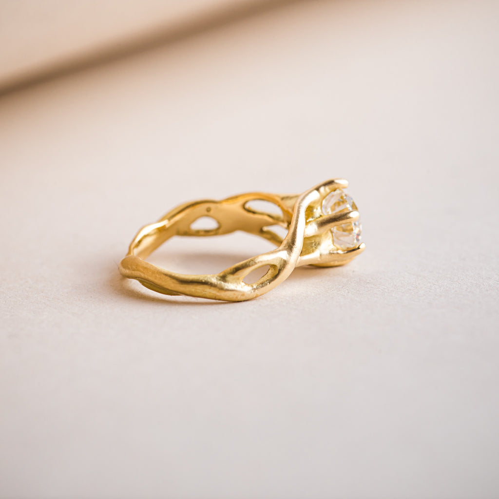 Etwined 18ct yellow gold ring with a branch like design that weaves around a brillliant round diamond
