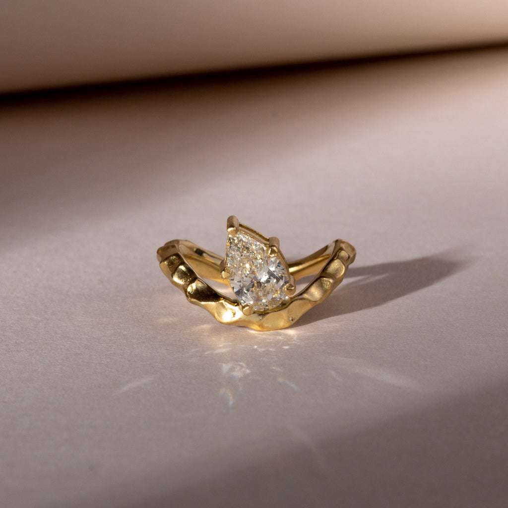 Pear shaped diamond on yellow gold wave band
